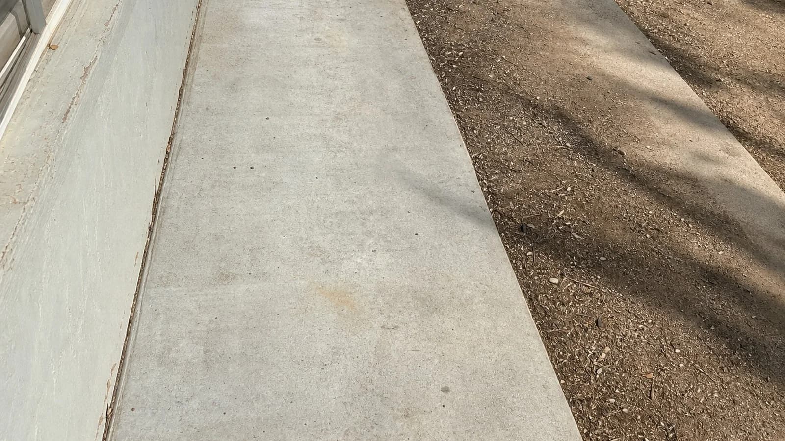 Palmdale side yard after cleanup with the concrete walkway swept and the dirt strip left natural.