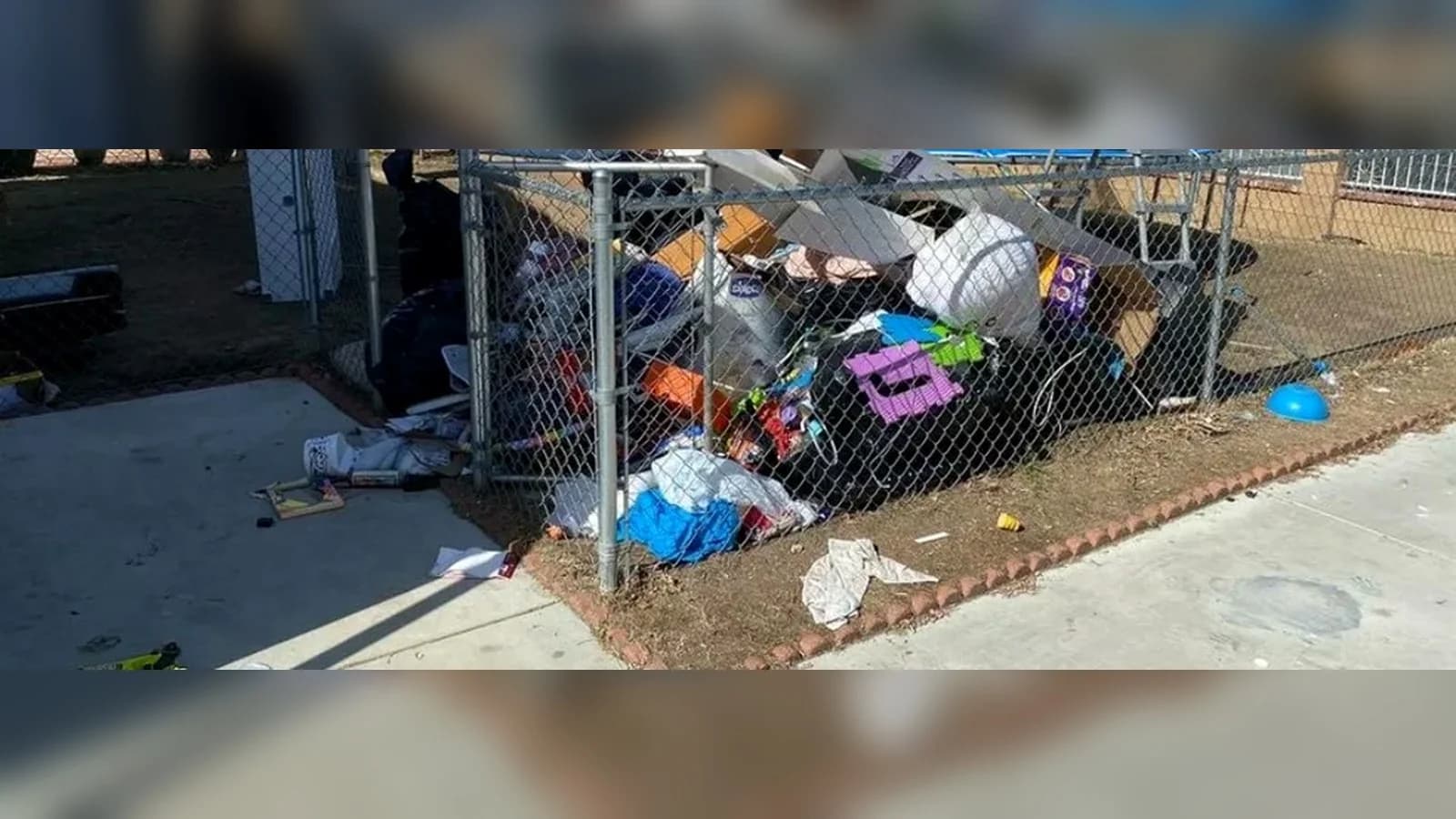 Palmdale fenced yard before cleanup with black bags, boxes, toys, cushions, and loose debris.