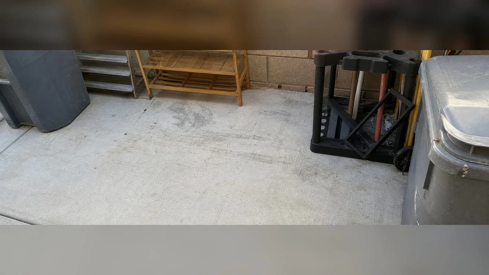 Lancaster patio corner after cleanup with the concrete swept and permanent bins left alone.