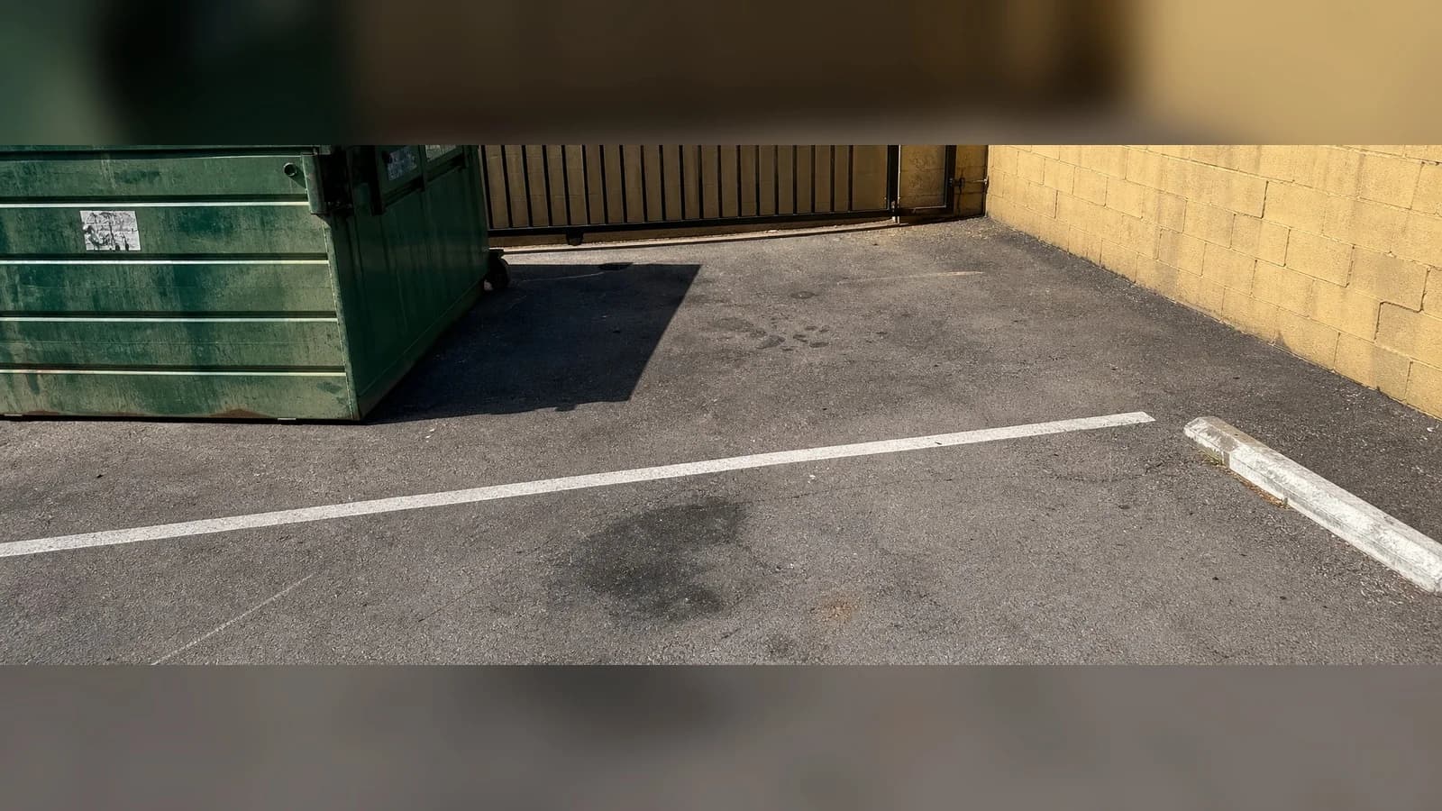 Palmdale parking area after cleanup with the asphalt swept and the dumpster left in place.