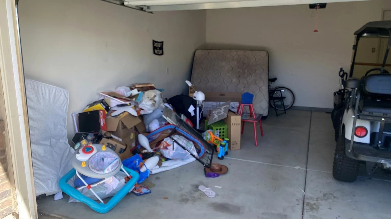 Garage filled with boxes, a mattress, toys, and household junk before removal.