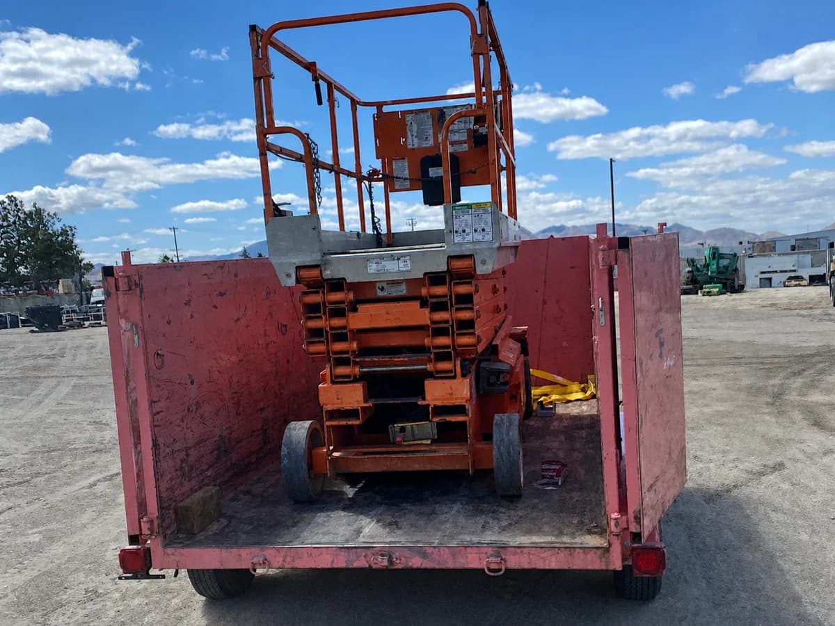 A commercial scissor lift secured inside Pinky's trailer for equipment transport.