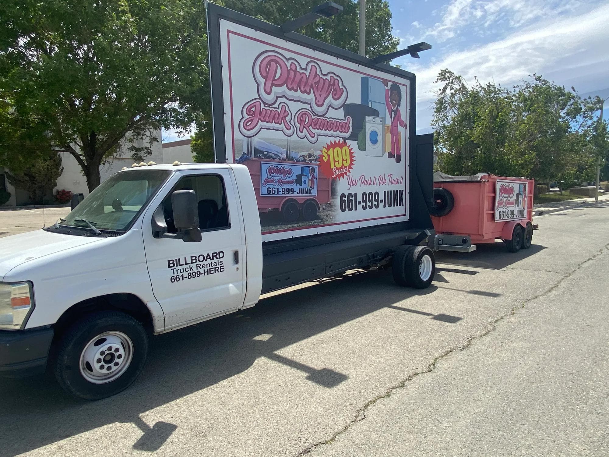 Pinky's billboard truck parked with the bright pink junk-removal trailer attached.