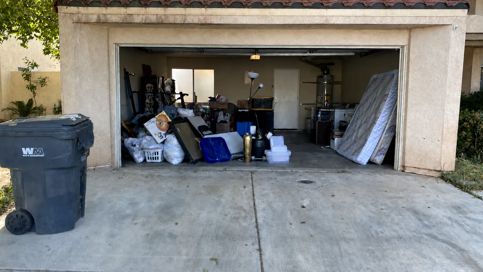 Palmdale garage before Pinky's Junk Removal cleared the mattress, bags, boxes, and household clutter.